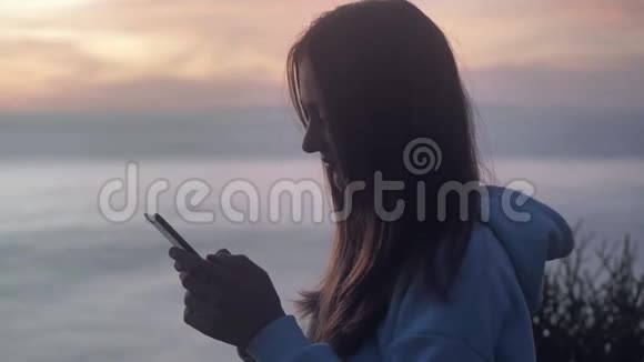 青少年在日落背景下使用智能手机上的社交网络通信4k视频的预览图