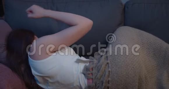 女孩用手敲打沙发枕头的后景年轻女子躺在沙发上裹着毯子看上去很漂亮视频的预览图
