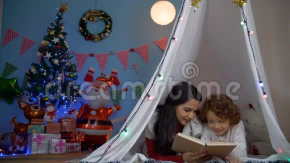 快乐的印度母亲在晚上给他的小儿子读故事书圣诞快乐视频的预览图