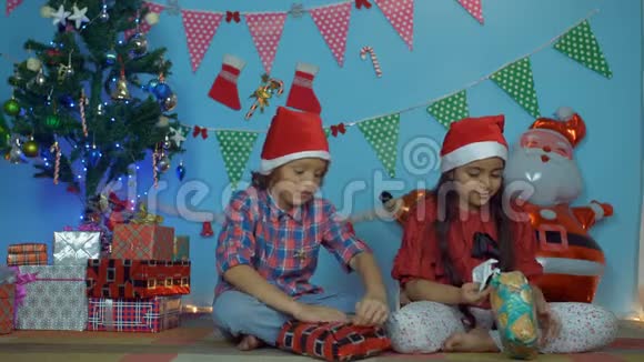可爱的小孩在圣诞树旁打开圣诞礼物视频的预览图