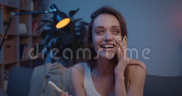 幸福的女人坐在沙发上做怀孕测试在智能手机上说话哭泣兴奋的女孩说视频的预览图