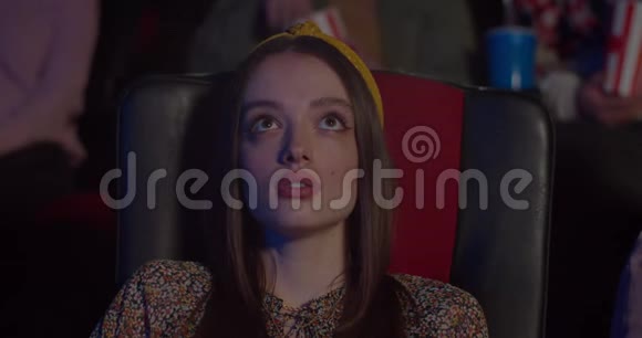 年轻的集中妇女在电影院观看和欣赏激动人心的电影坐在椅子上的漂亮的千禧女孩视频的预览图