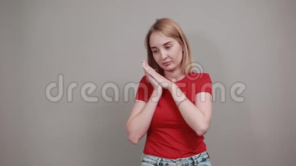 兴奋的年轻女子穿着红色衬衫双手紧贴着灰色的脸视频的预览图