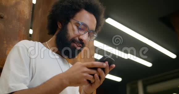 在使用智能手机与朋友交流时好看的男人微笑的底部视图三十岁的大胡子视频的预览图