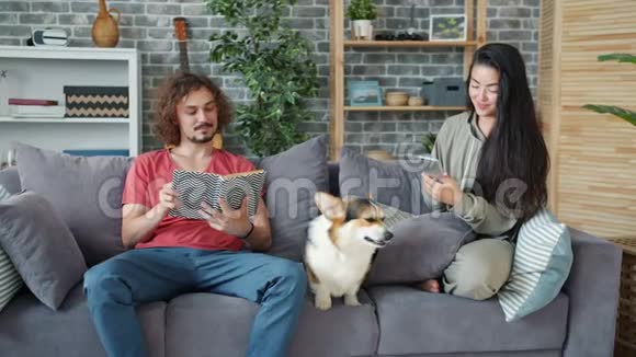 女友和男友用智能手机看书爱抚科吉狗视频的预览图