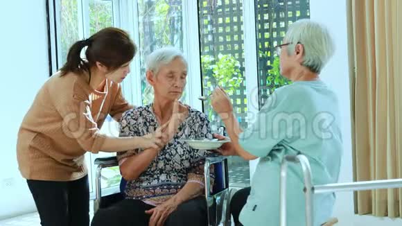 亚洲的女儿老年妇女或家庭朋友在轮椅上喂养老年病人或母亲劳累厌倦食物少吃食物视频的预览图