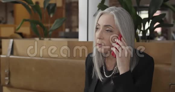 在智能手机上聊天的中年漂亮女商人上了年纪的女老板坐在沙发上视频的预览图