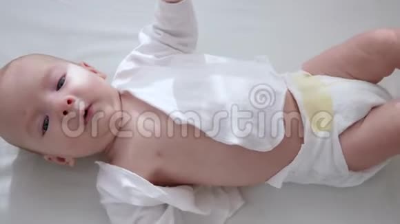 尿布上快乐的婴儿躺在室内的白色床上光线自然视频的预览图