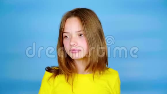 一个穿黄色T恤的少女正在蓝色背景上看着并有复印空间视频的预览图