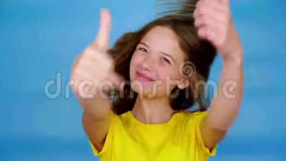 穿着黄色t恤的快乐少女微笑着竖起大拇指喜欢并看着镜头视频的预览图