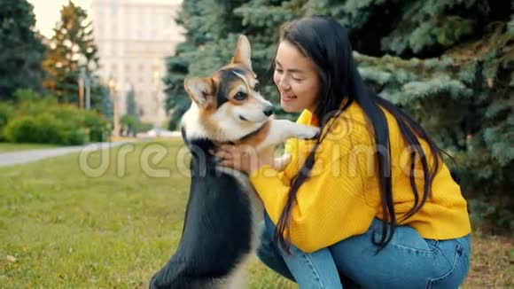 亚洲女孩在城市公园户外拥抱和亲吻科吉狗的慢动作视频的预览图