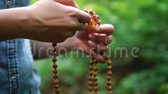 手中的祈祷珠女性手拿念珠在绿色的自然背景上向上帝祈祷宗教的灵性视频的预览图