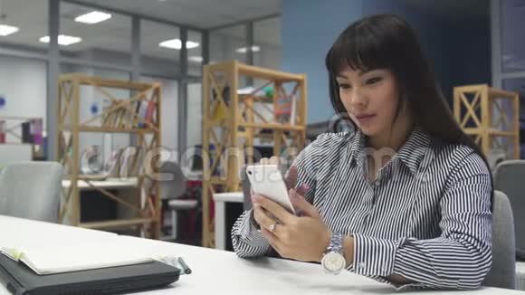 有智能手机的亚洲女孩在办公室视频的预览图