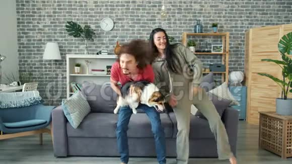 快乐的男人和女友一起跳舞抱着科吉小狗在家玩得很开心视频的预览图