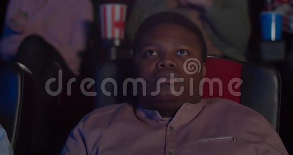 年轻人坐着看有趣电影的肖像一个在电影院看电影的非洲人视频的预览图