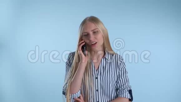 漂亮的年轻女士在蓝色背景下通过智能手机与某人交谈视频的预览图