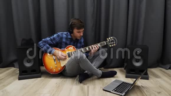 人类学习弹吉他戴着耳机练习弹电吉他的人年轻人一边弹吉他视频的预览图