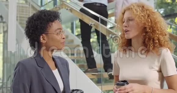 两名不同种族的妇女办公室工作人员站在办公室走廊上交谈接近成功的年轻女性视频的预览图