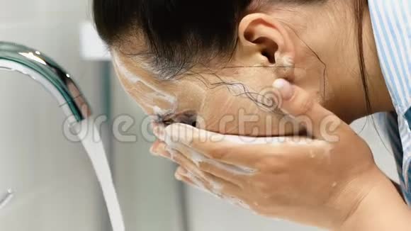 女孩洗了她的脸面涂奶油肥皂慢动作关门视频的预览图