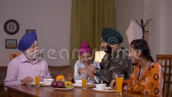 快乐的印度锡克族父亲是陆军军官早餐时在餐桌上享受欢乐时光视频的预览图