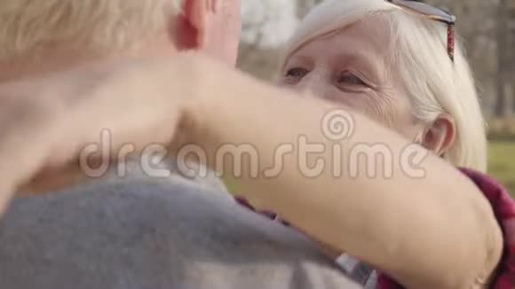 一个快乐的高加索族女人拥抱她可爱的丈夫的特写肖像成熟的退休夫妇阳光明媚视频的预览图