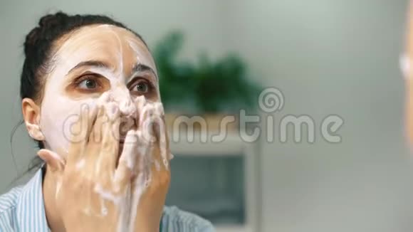 一个年轻的女人在浴室里照顾自己洗衣服照镜子视频的预览图