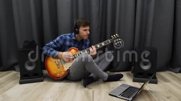 男性用电吉他演奏穿着专业耳机和休闲服的年轻人用笔记本练习吉他演奏视频的预览图