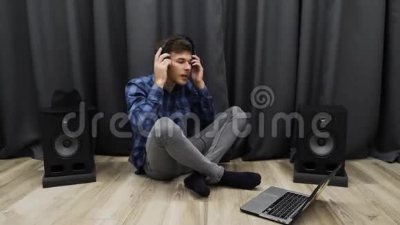 年轻人用耳机听音乐和唱歌男人戴上耳机坐在地板上唱歌视频的预览图