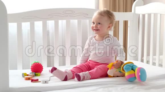 孩子们笑着坐在白色的床上坐在玩具中间视频的预览图