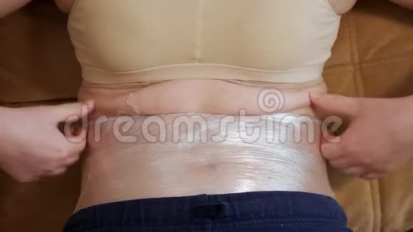 女人腹部的特写包裹在塑料薄膜里视频的预览图