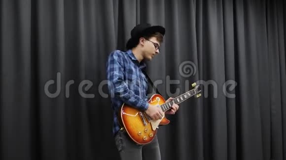 他用电吉他演奏情感吉他独奏年轻的职业音乐家吉他手黑色时尚帽子演奏视频的预览图