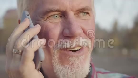一个成熟的白人男人的特写脸站在秋天的公园里用智能手机说话高级欧洲球员结束视频的预览图