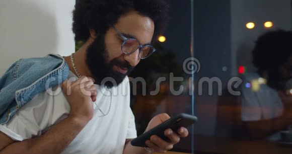 戴眼镜的帅哥站在商店橱窗附近时肩膀上拿着夹克30岁大胡子男的侧视视频的预览图