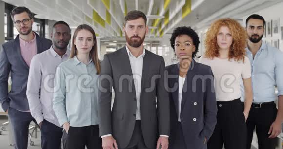 站在现代办公室的自信团队的肖像成功的男女办公室工作人员寻找镜头视频的预览图