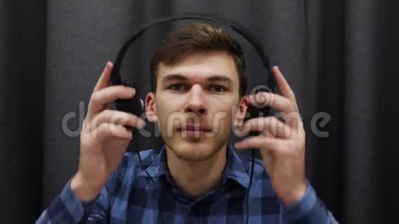 耳机听音乐的人的肖像年轻的微笑男性戴上耳机在灰色背景下听歌视频的预览图