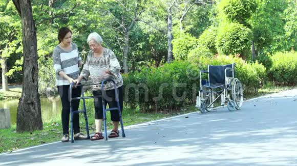 亚洲老年妇女在膝关节手术后的康复过程中使用助行器年轻的护理人员协助让老人安心视频的预览图