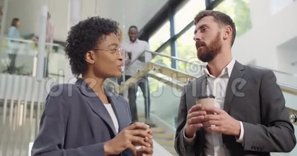 男人和女人的办公室工作人员交谈和站在咖啡纸杯不同种族的同事视频的预览图