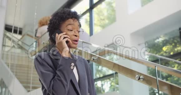 开朗的女办公室秘书在智能手机上聊天拿着纸杯漂亮的笑脸女经理视频的预览图