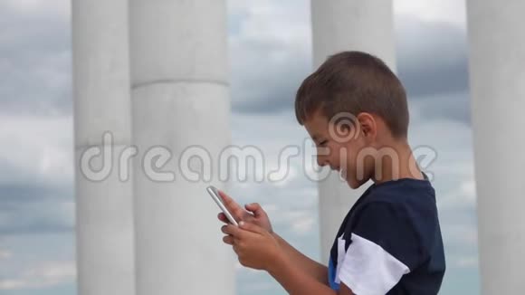 男孩在手机上打印一条信息并微笑视频的预览图