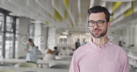 开朗的男上班族戴着眼镜转头对着镜头微笑快乐胡子男创业公司老板视频的预览图