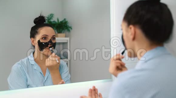 一个年轻的女孩在她的脸上涂了一个清洁剥皮面具视频的预览图