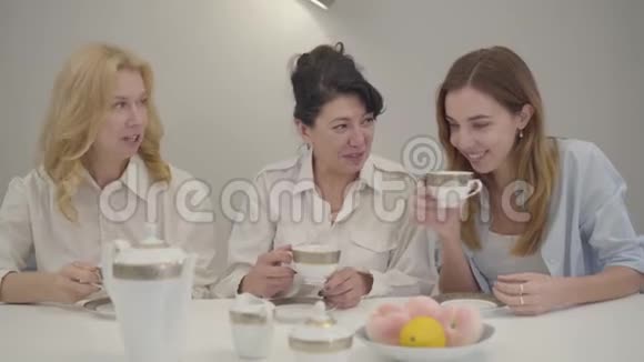 三个不同年龄的白人妇女坐在桌子旁喝茶或咖啡聚集的朋友或家人视频的预览图
