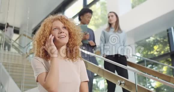 在空闲时间在智能手机上微笑和聊天的快乐白种人女性办公室秘书美丽的女人视频的预览图