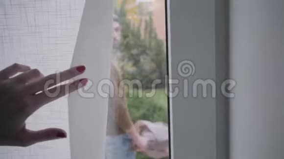 玻璃门上的窗帘打开了成年白种人的白发男子站在门后手里拿着一束紫罗兰色的玫瑰视频的预览图