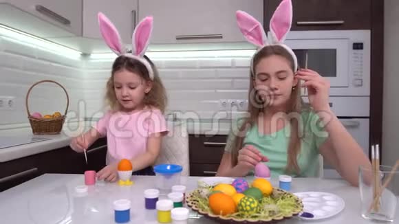 复活节快乐两个姐妹画复活节彩蛋为复活节做准备的快乐家庭孩子可爱的小女孩视频的预览图