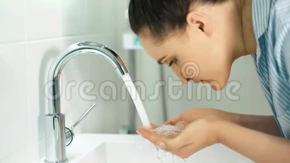 女孩洗了她的脸浴室里的女孩早上做水处理视频的预览图