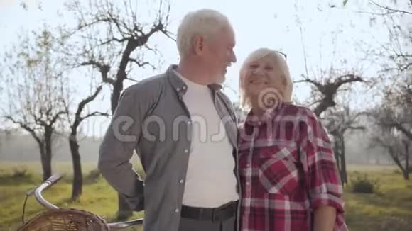 快乐的高白种人夫妇站在雾蒙蒙的公园里微笑着女人指着别的东西退休人员视频的预览图