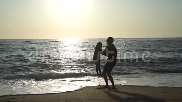 父亲在日落时把女儿扔在海滩上视频的预览图