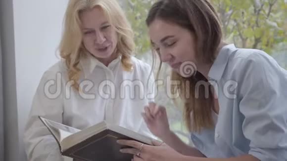 一位年轻可爱的白种人女人的特写镜头与年长的金发女士合影妈妈和女儿在视频的预览图