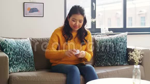 在家带耳机和智能手机的亚洲女性视频的预览图